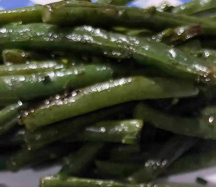 Oven roasted green beans on white and blue plate.