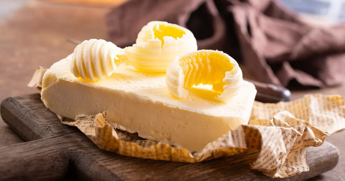 Fresh butter on paper atop a cutting board.