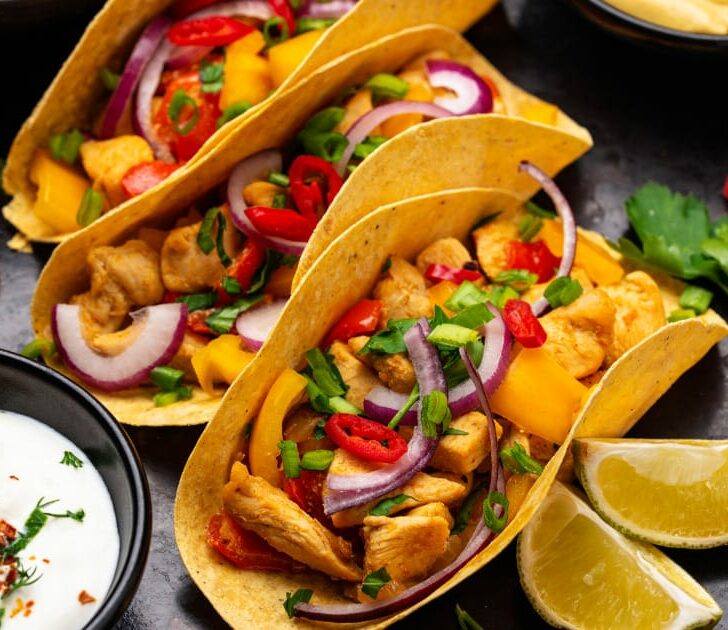 Tacos arranged on plate surrounded by toppings.