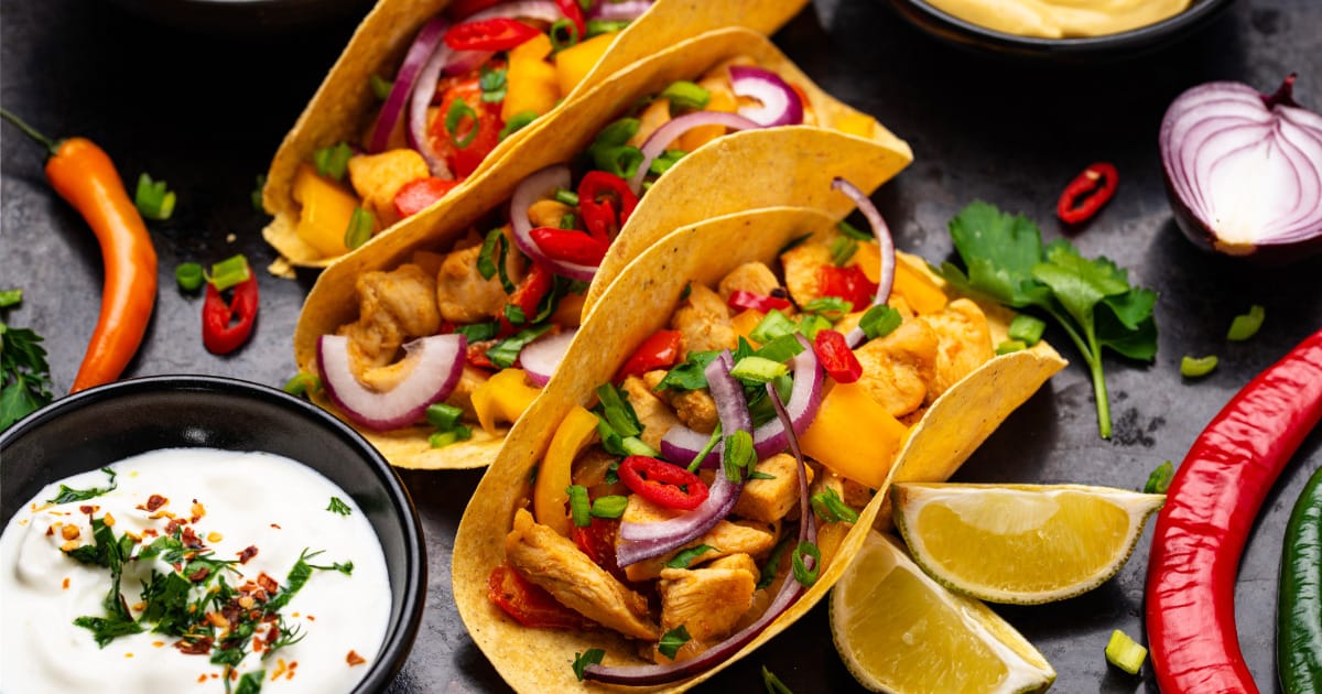 Tacos arranged on plate surrounded by toppings.