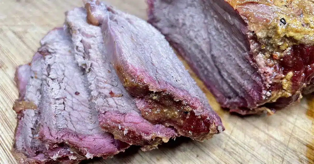 Sliced smoked chuck tender roast on cutting board.