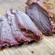 Sliced smoked chuck tender roast on cutting board.