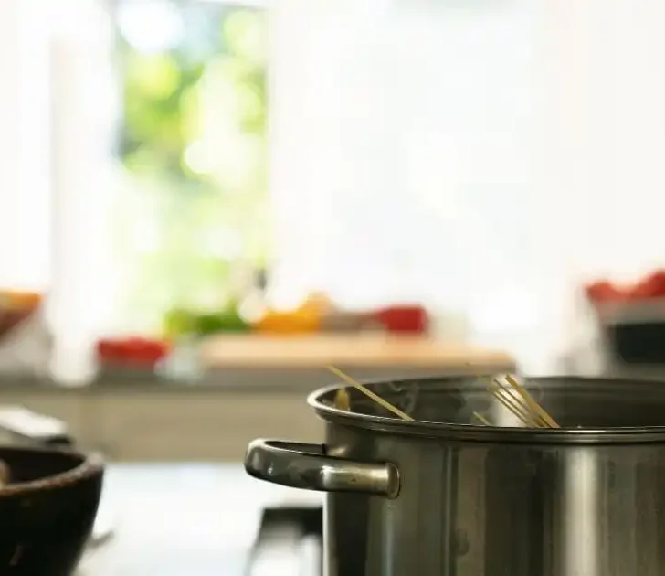 Pot on stove with uncooked pasta.