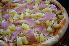 Unbaked Hawaiian pizza with ham, pineapple, and cheese on crust
