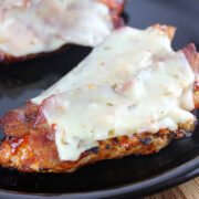 Juicy grilled chicken breast layered with bacon and melted pepper jack cheese on a black plate