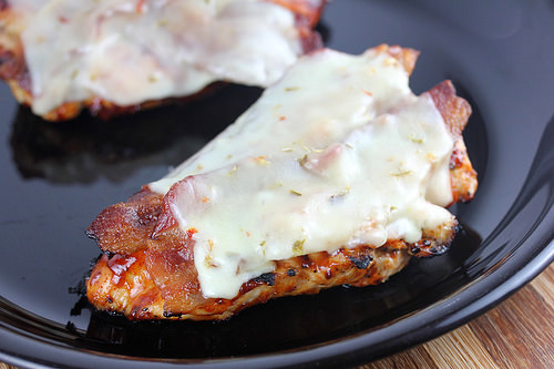 Juicy grilled chicken breast layered with bacon and melted pepper jack cheese on a black plate