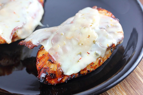 Grilled BBQ chicken breast topped with melted pepper jack cheese on a black plate
