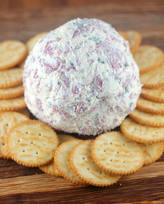 Cheese ball with crackers on wooden board