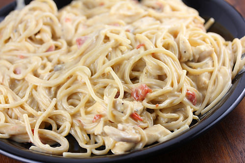 Plate of creamy cheesy chicken spaghetti with diced tomatoes