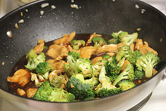 Chicken and broccoli stir fry cooking in a wok with sauce