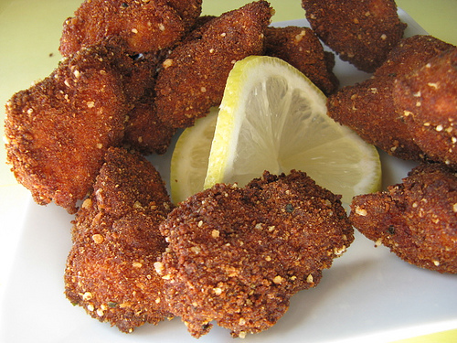 Plate of crispy fried chicken nuggets with lemon wedge