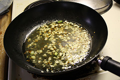 Garlic and red pepper flakes frying in oil in a wok