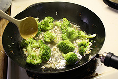 Broccoli florets simmering with garlic in a wok