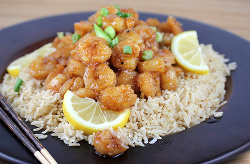 Plate of lemon pepper shrimp on rice with lemon wedges