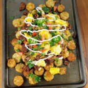 Loaded chorizo totchos with eggs and melted cheese on a tray