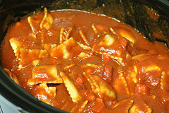 Layering ravioli and tomato sauce in a slow cooker