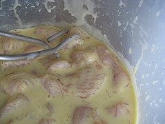 Raw chicken pieces marinating in a creamy batter mixture