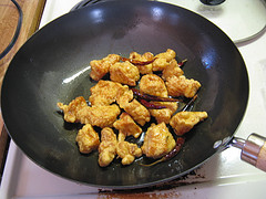 Fried chicken pieces with dried chili peppers in a wok before sauce is added