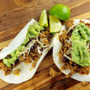 Ground pork tacos with guacamole and shredded cheese on tortillas