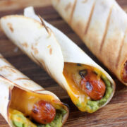 Hot dog tacos wrapped in tortillas with cheddar and guacamole