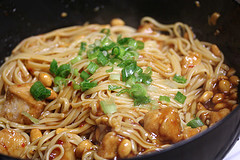Wok of kung pao linguine with chicken, peanuts, and green onions