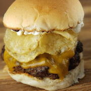 Close-up of burger stacked with cheddar cheese, potato chips, and mayonnaise