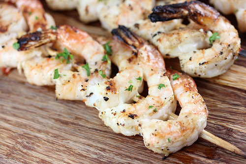 Close-up of grilled shrimp skewers sprinkled with chopped parsley