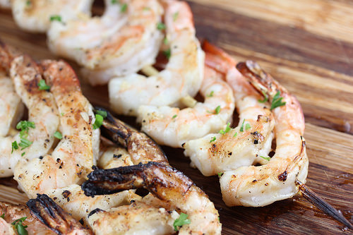 Juicy grilled shrimp skewers with sear marks, served on a wooden surface