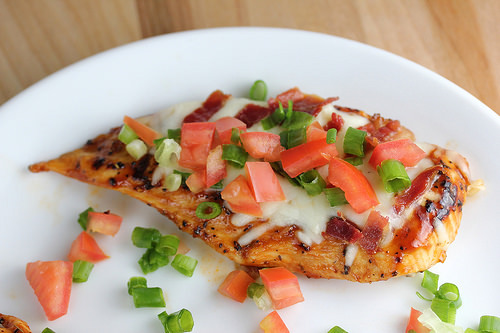Grilled chicken breast topped with melted cheese, bacon, tomatoes, and green onions