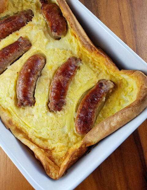 Close-up of toad in the hole showing browned sausages in baked batter