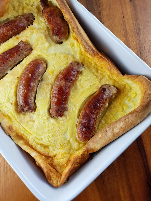 Close-up of toad in the hole showing browned sausages in baked batter