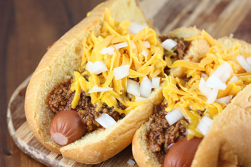 Cincinnati cheese coney topped with chili, shredded cheddar, and diced onions