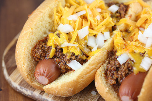 Cincinnati cheese coney topped with chili, shredded cheddar, and diced onions