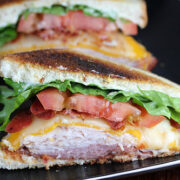Clubhouse sandwich with turkey, bacon, cheese, lettuce, and tomato on toasted bread