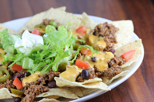 Close-up of nachos topped with beef, cheese, and lettuce