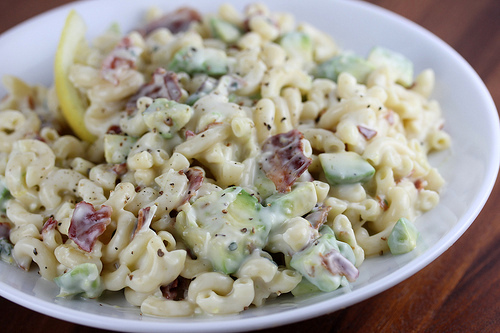 Close-up of creamy bacon avocado pasta salad sprinkled with black pepper