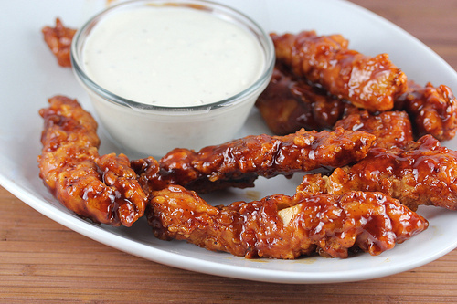 Plate of saucy BBQ chicken strips paired with a small bowl of ranch dressing