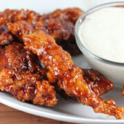 Close-up of BBQ chicken strips glazed in sauce with ranch dip on the side