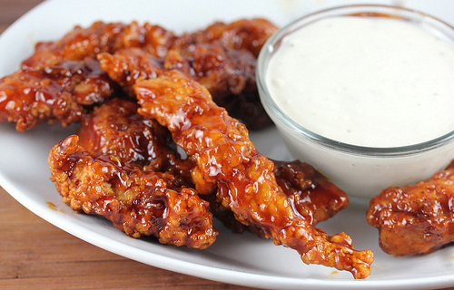 Close-up of BBQ chicken strips glazed in sauce with ranch dip on the side
