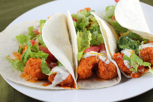 Close-up of buffalo chicken tacos filled with lettuce, tomato, and ranch dressing