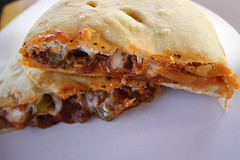 Close-up of baked calzone cut open to show cheesy filling