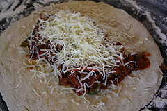 Calzone dough topped with meat sauce and shredded cheese