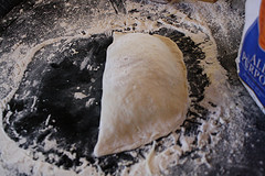Unbaked calzone folded on floured surface