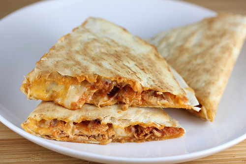Plate of cheesy chicken tinga quesadillas cut into triangles