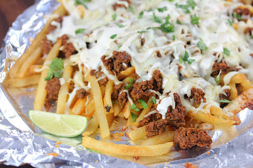 Cheesy chorizo fries garnished with lime and herbs