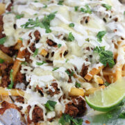 Loaded fries with chorizo, cheese, and lime wedges