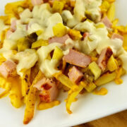 Close-up of Cuban fries loaded with ham, pickles, and melted cheese