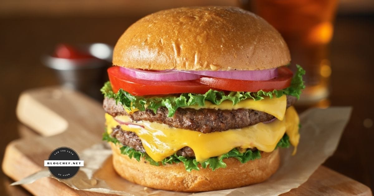 close up of prepared hamburger with cheese and toppings