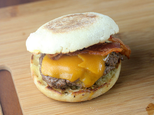Bacon cheeseburger on an English muffin on wooden board