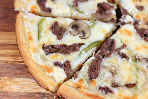 Philly cheesesteak pizza topped with mushrooms and green peppers